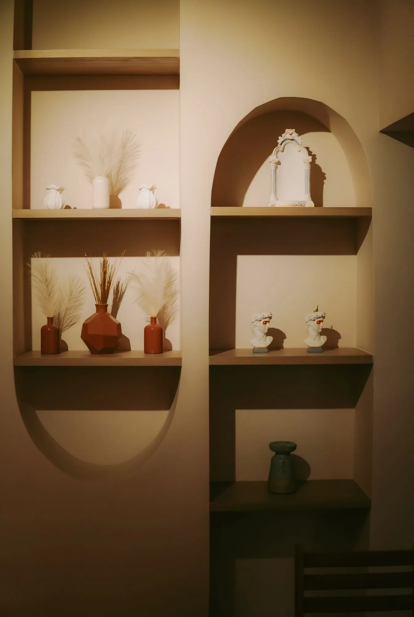 Nichos en arco con piezas de cerámica y flores secas en un salón de CAELUS