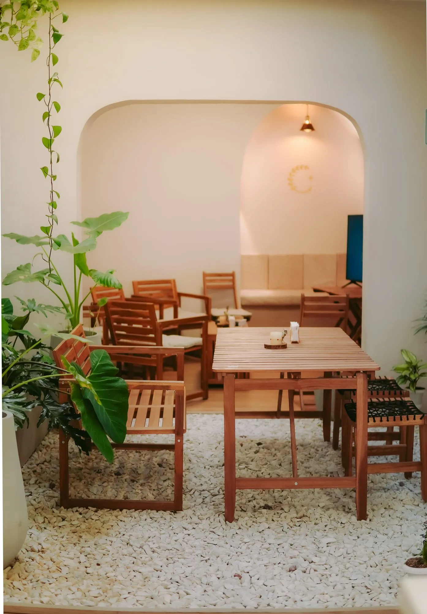 Nicho en arco iluminado, con mesa de madera y plantas, en un salón de CAELUS