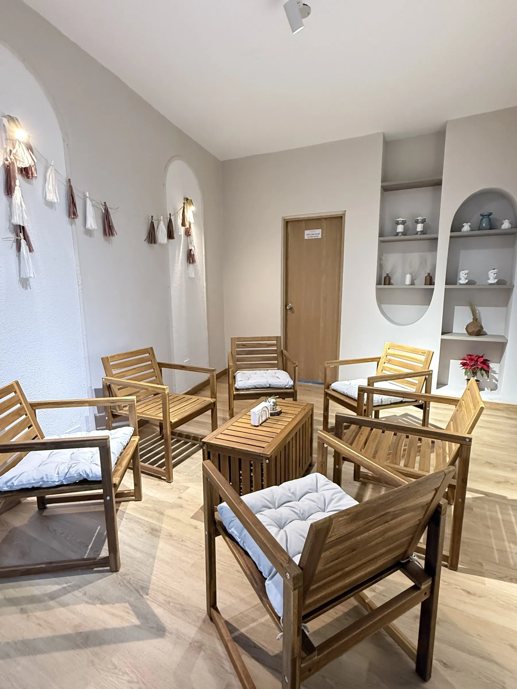 Rincón de sillones de madera con cojines en un salón de CAELUS