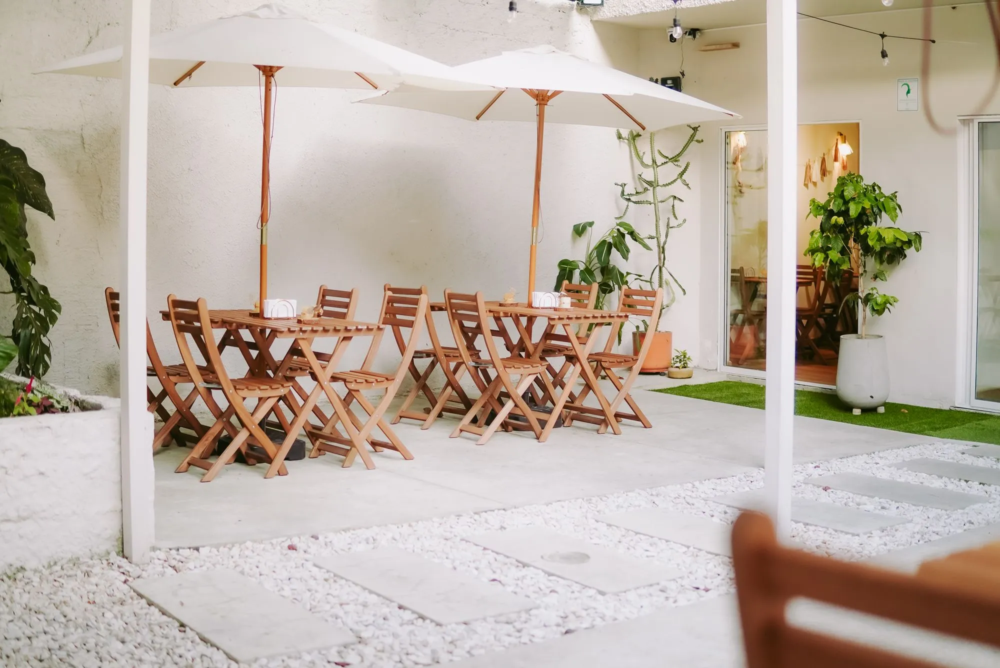 Terraza de CAELUS en Laureles con mesas de madera y sombrillas blancas